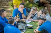 GODZone Race Director Warren Bates (bottom left holding unit) demonstrates to racers how the YB Tracking Unit works.